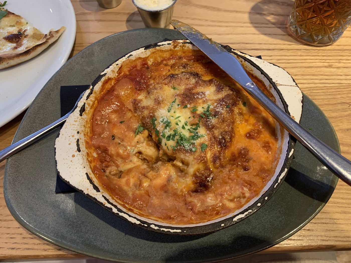 A baked dish of melted cheese and tomato in a black dish